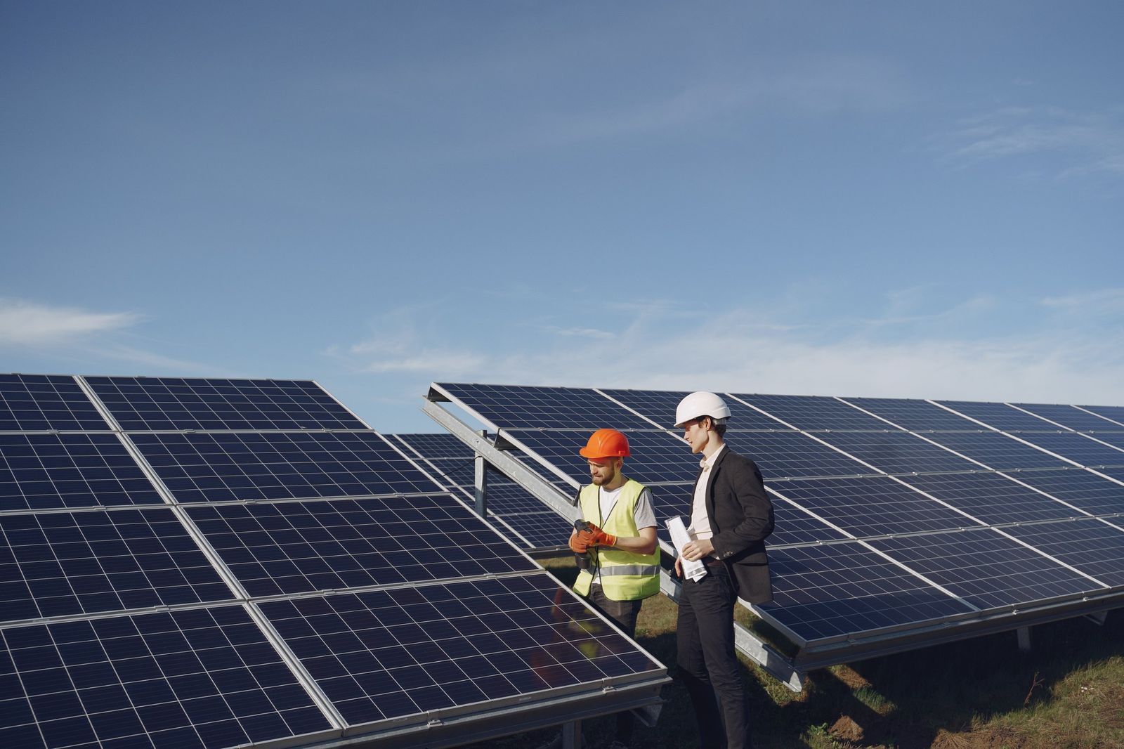 Técnico e investidor de capacete conversando entre as placas de uma usina solar