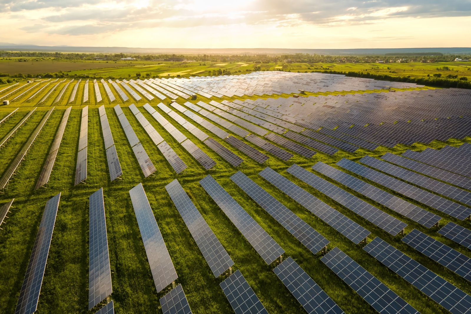 Vista aérea de uma usina solar com fileiras de placas em um campo verde